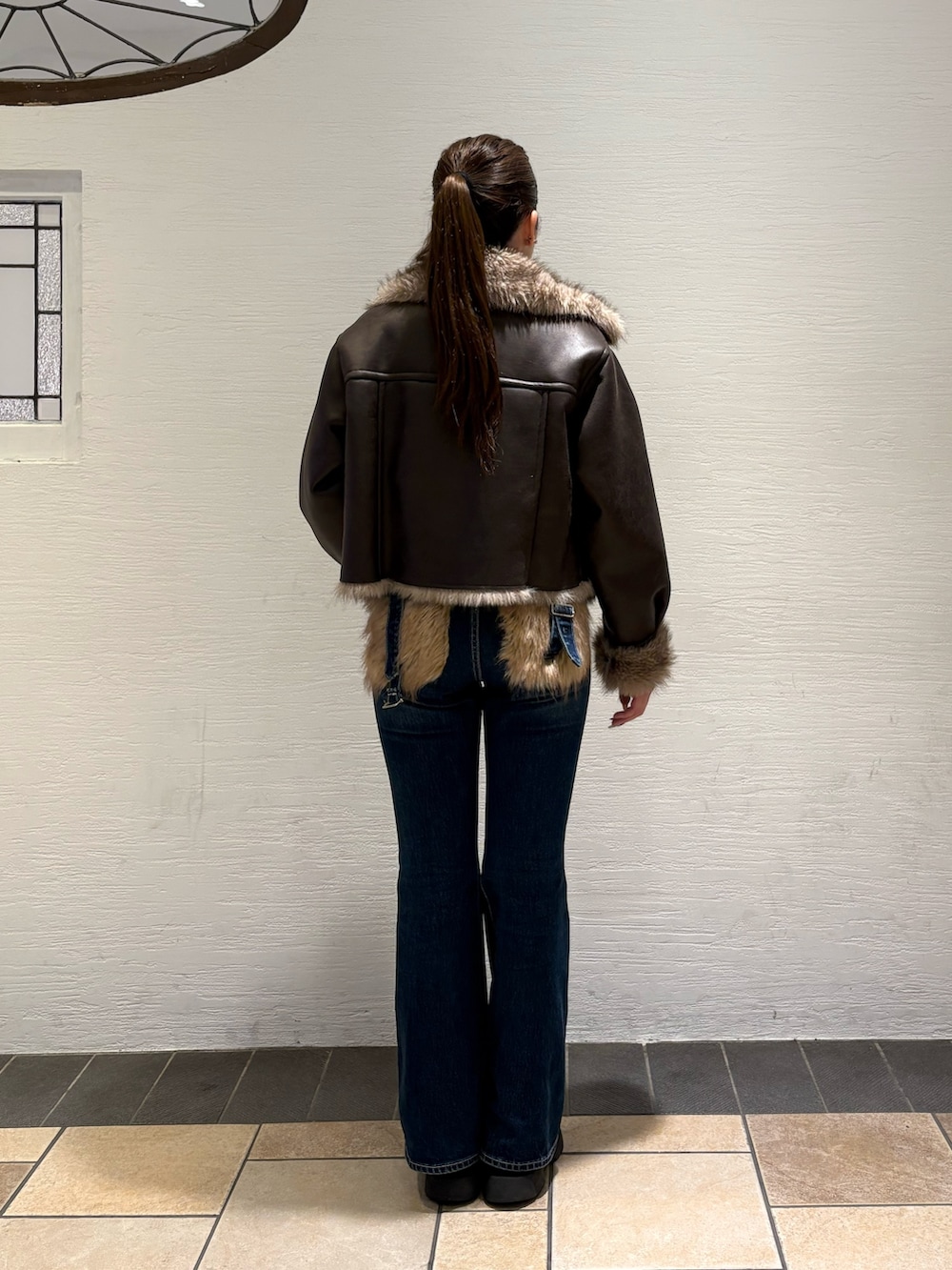 ブルー系のデニムパンツ、ブラック系のブーツ、ブラウン系のブルゾンを着用したレディースの秋コーディネートの3枚目の写真