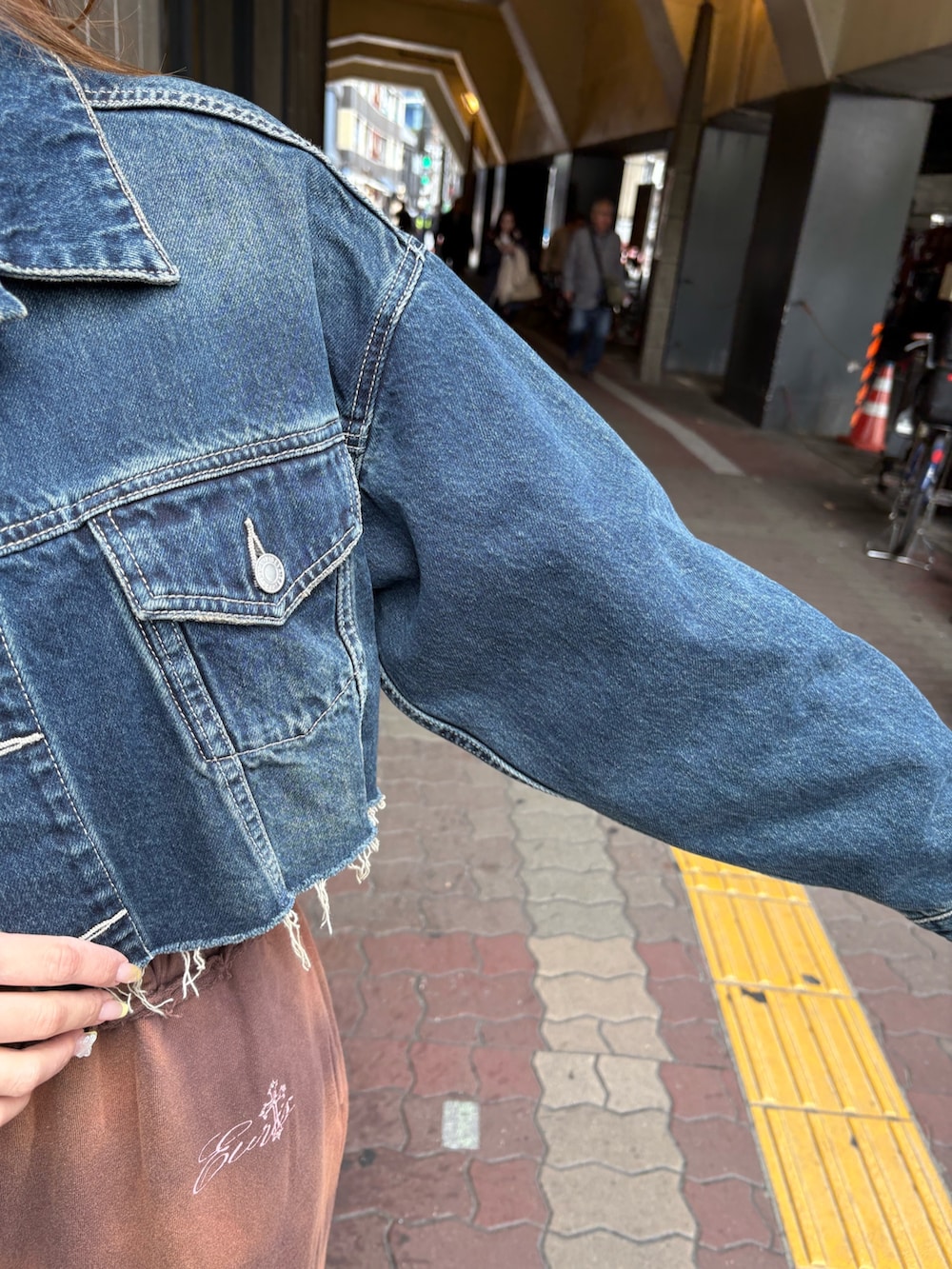 ブルー系のデニムジャケット、ブラウン系のスウェットパンツ、ブラック系のブーツを着用したレディースの春コーディネートの5枚目の写真