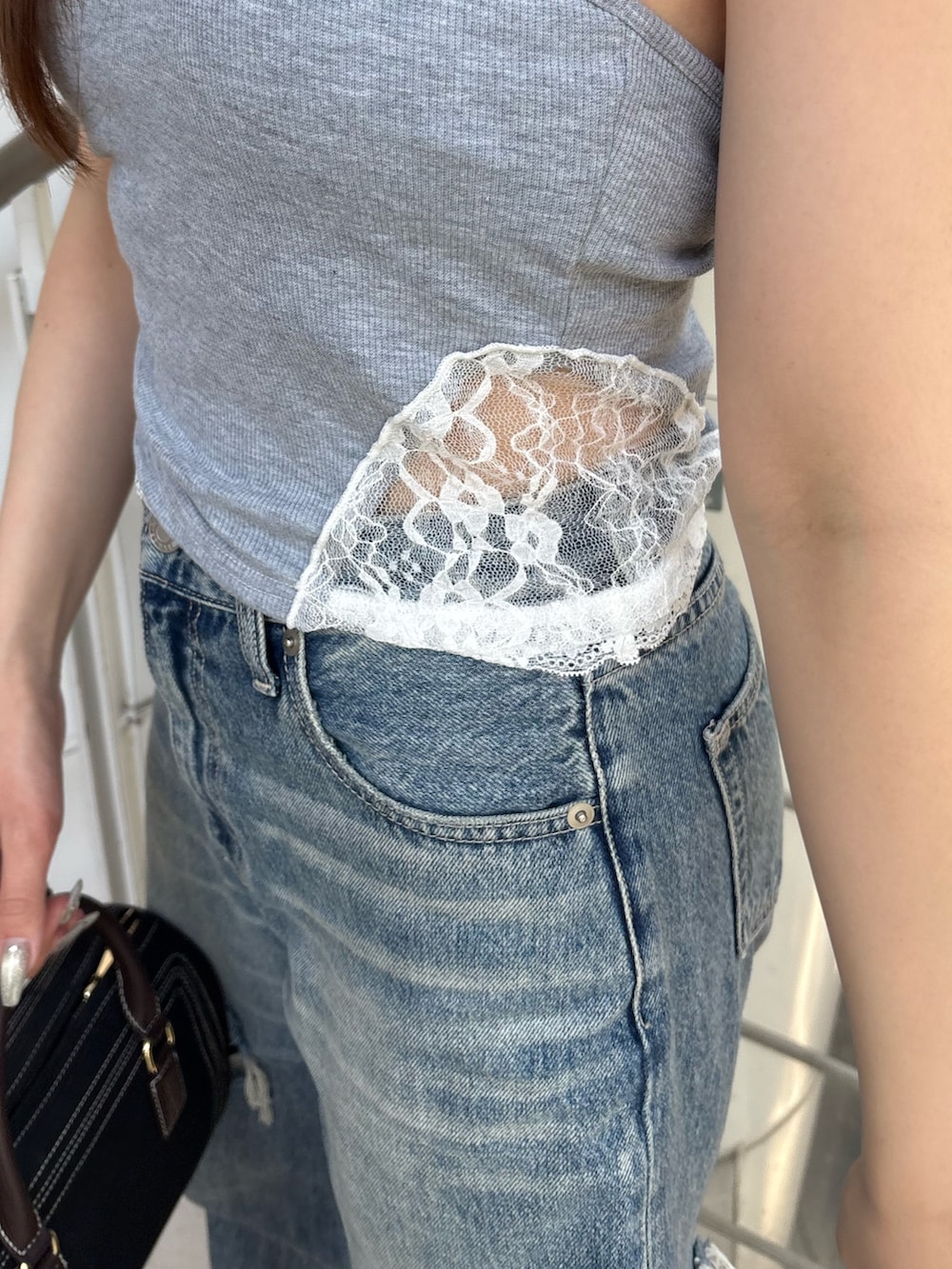 ブルー系のデニムパンツ、ブラック系のボストンバッグ、ブラック系のブーツを着用したレディースの夏コーディネートの5枚目の写真