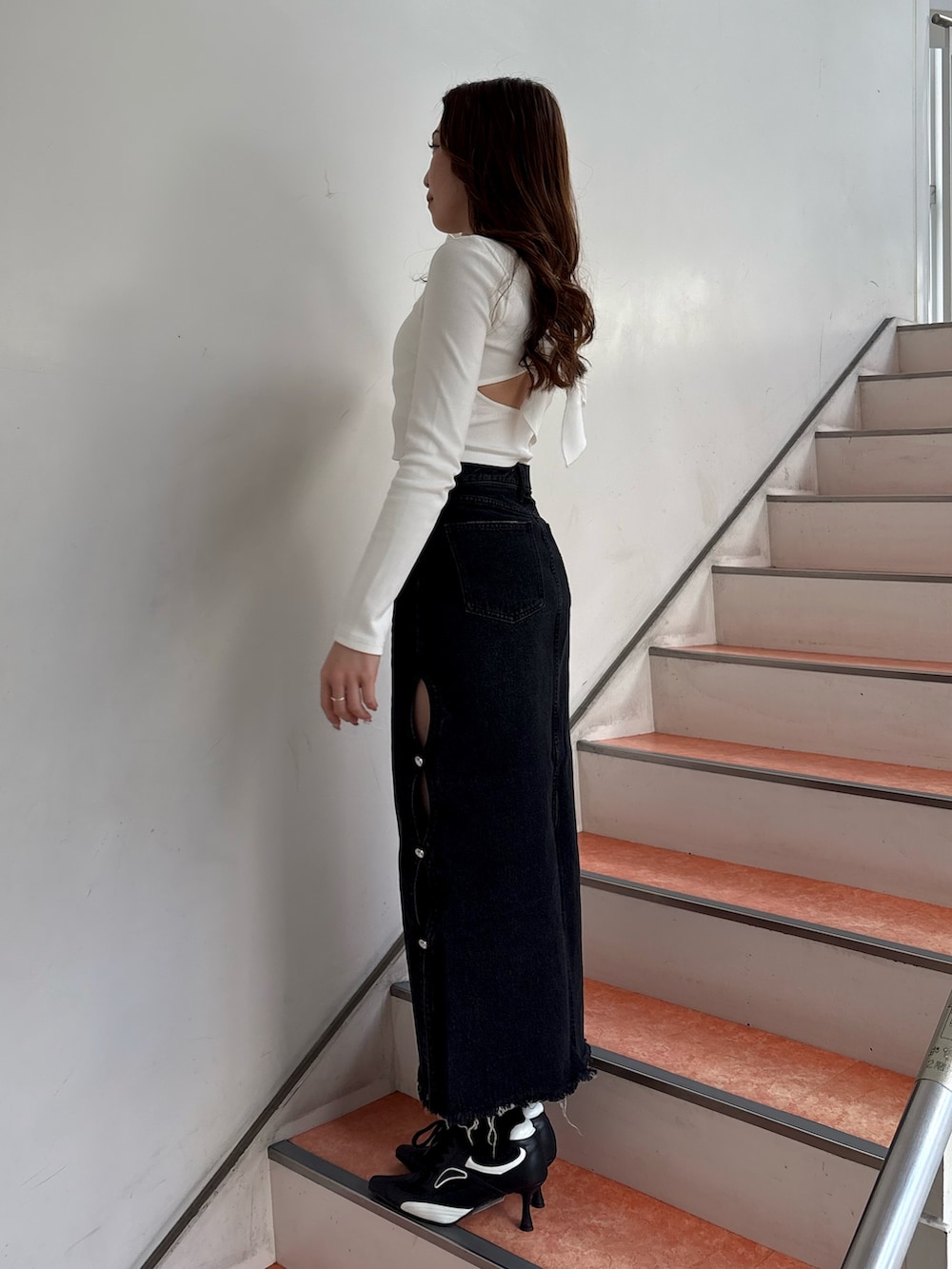 ホワイト系のTシャツ/カットソー、ブラック系のデニムスカート、ブラック系のパンプスを着用したレディースの春コーディネートの2枚目の写真