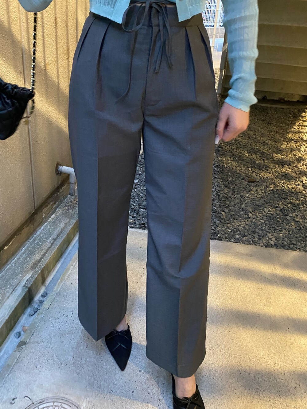 ブルー系のニット/セーター、グレー系のその他パンツ、ブラック系のサンダルを着用したレディースの春コーディネートの6枚目の写真