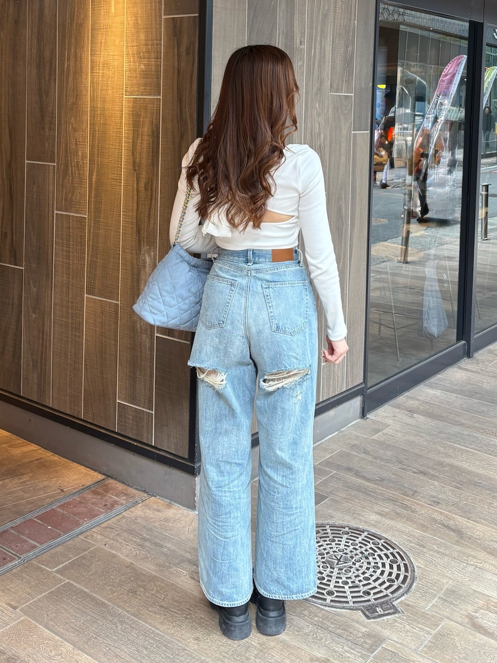 ホワイト系のTシャツ/カットソー、ブルー系のデニムパンツ、ブラック系のブーツを着用したレディースの春コーディネートの3枚目の写真