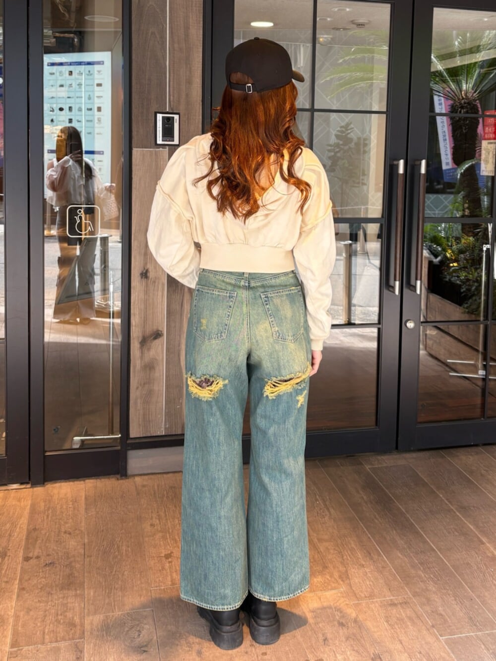 ブラック系のブーツ、ブルー系のデニムパンツ、ホワイト系のパーカーを着用したレディースの春コーディネートの3枚目の写真