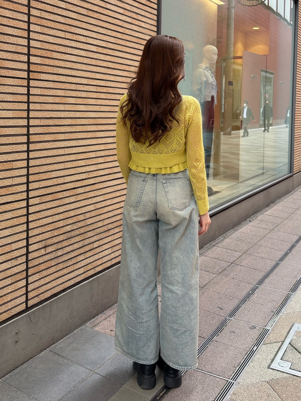 イエロー系のカーディガン/ボレロ、ブラック系のブーツ、ブルー系のデニムパンツを着用したレディースの春コーディネートの3枚目の写真