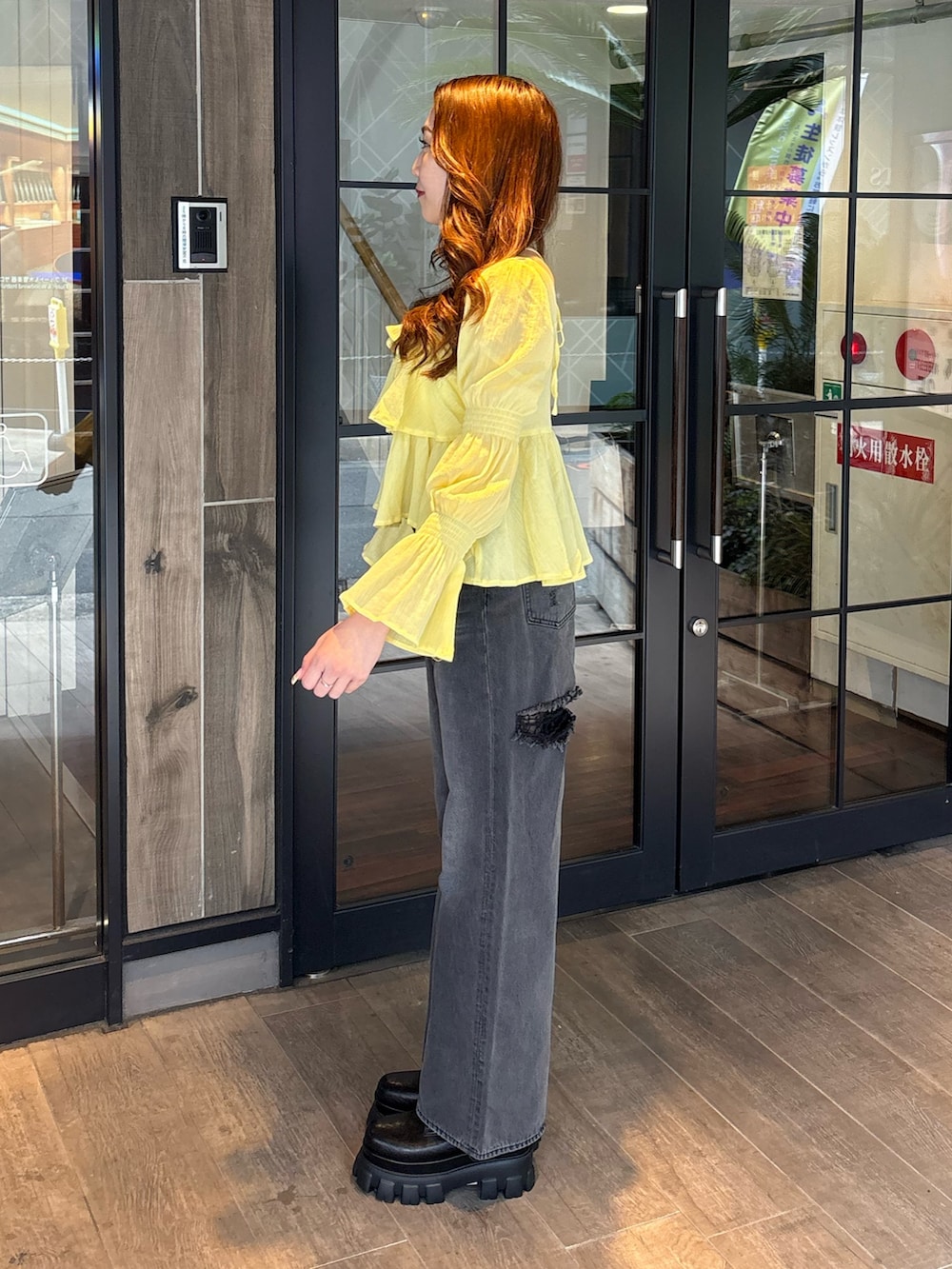 イエロー系のシャツ/ブラウス、ブラック系のデニムパンツ、ブラック系のブーツを着用したレディースの春コーディネートの2枚目の写真