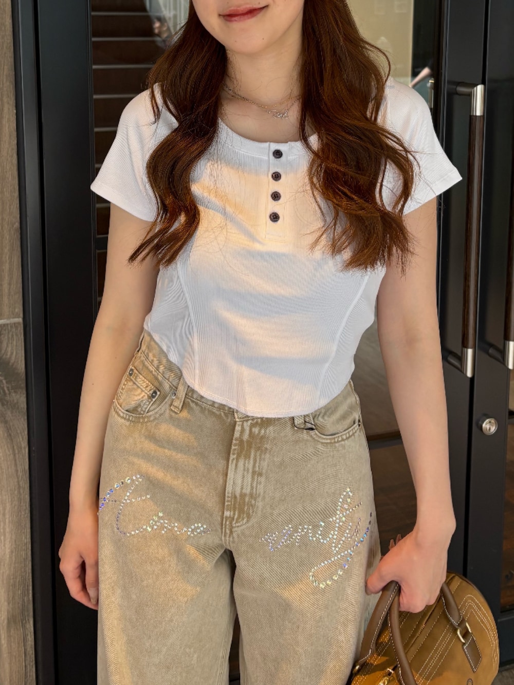 ブラウン系のボストンバッグ、ベージュ系のデニムパンツ、ブラック系のブーツを着用したレディースの夏コーディネートの4枚目の写真