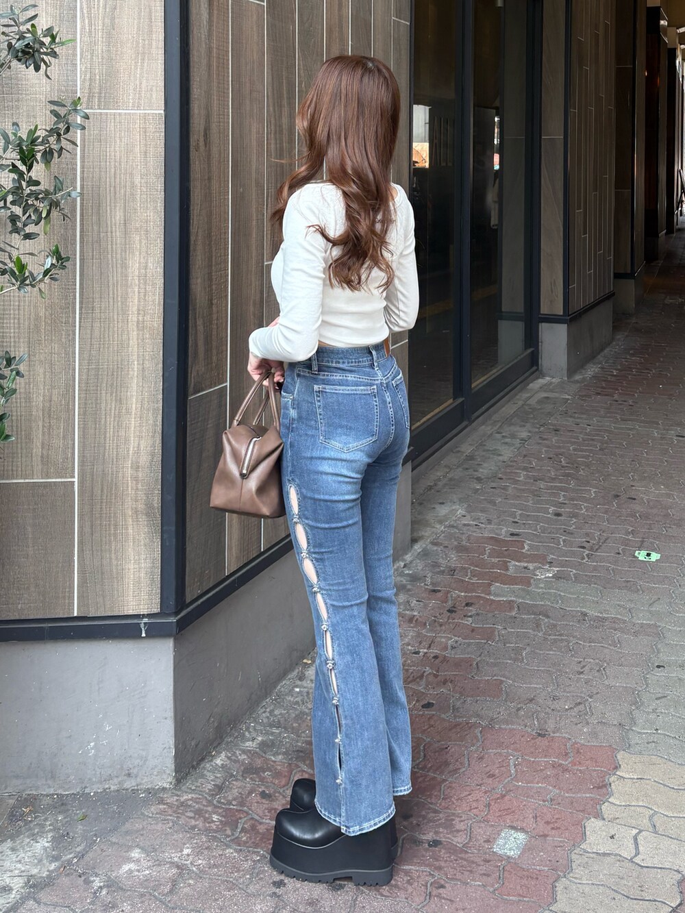 ホワイト系のTシャツ/カットソー、ブルー系のデニムパンツ、ブラック系のブーツを着用したレディースの冬コーディネートの2枚目の写真