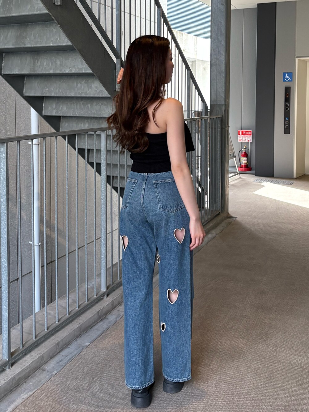 ブルー系のデニムパンツ、ブラック系のキャミソール、ブラック系のブーツを着用したレディースの春コーディネートの3枚目の写真