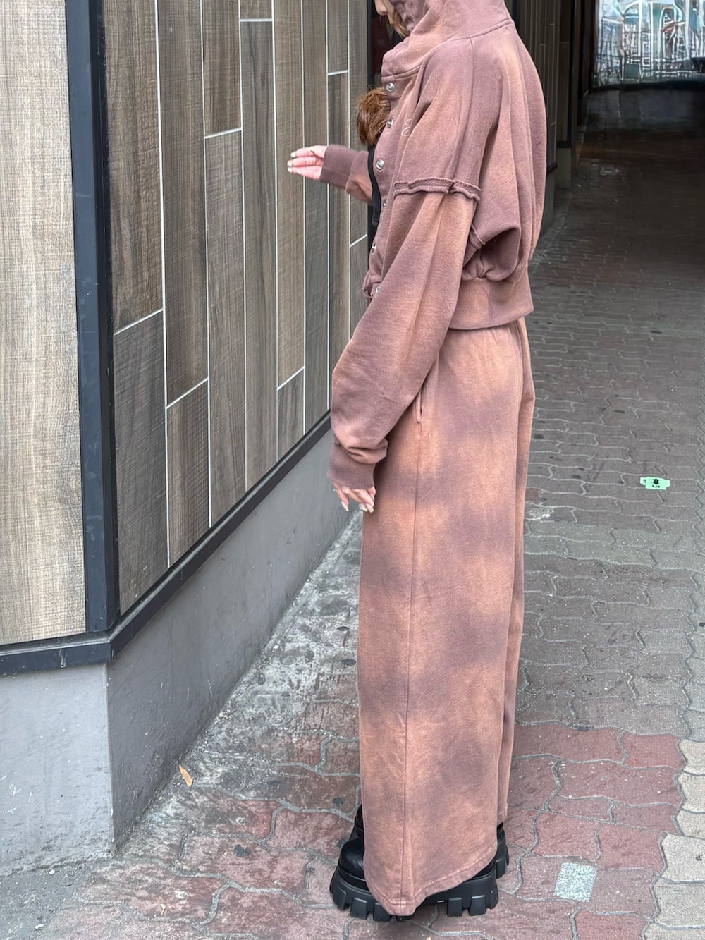 ブラウン系のスウェットパンツ、ブラック系のブーツ、ブラウン系のパーカーを着用したレディースの春コーディネートの2枚目の写真