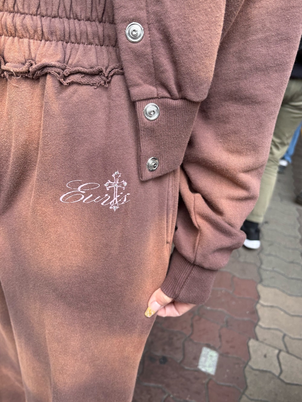 ブラウン系のスウェットパンツ、ブラック系のブーツ、ブラウン系のパーカーを着用したレディースの春コーディネートの6枚目の写真