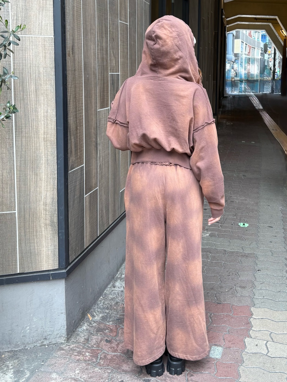 ブラウン系のスウェットパンツ、ブラック系のブーツ、ブラウン系のパーカーを着用したレディースの春コーディネートの3枚目の写真