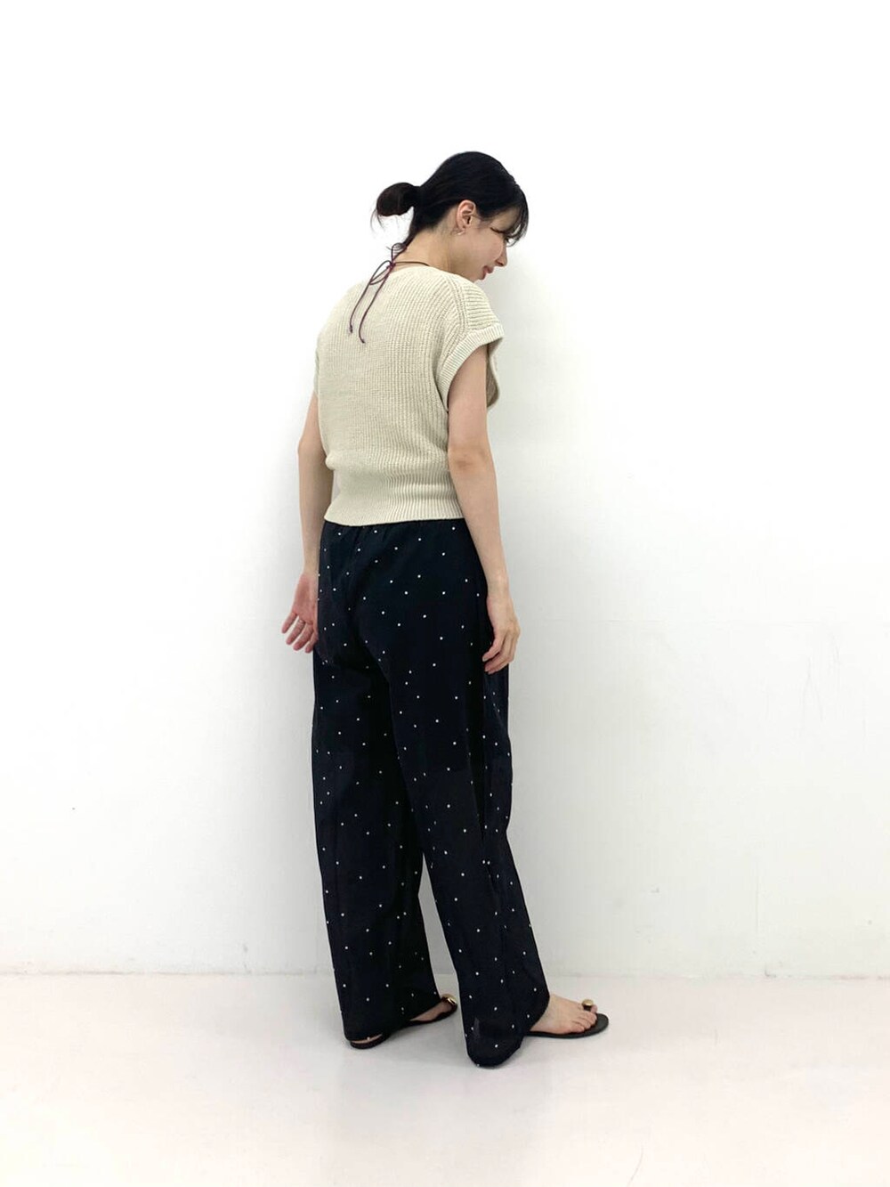 ブラウン系のその他パンツ、ベージュ系のベスト、ブラック系のサンダルを着用したレディースの夏コーディネートの2枚目の写真