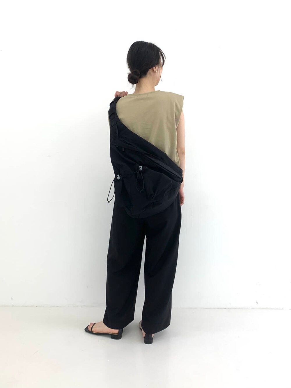 ブラック系のその他パンツ、ブラック系のサンダル、ベージュ系のTシャツ/カットソーを着用したレディースの夏コーディネートの2枚目の写真