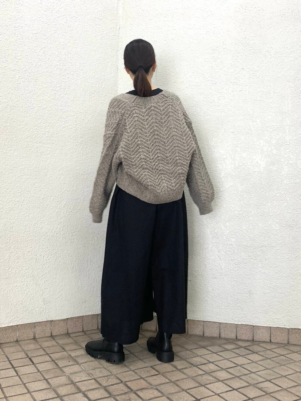 グレー系のニット/セーター、ブラック系のサロペット/オーバーオール、ブラック系のブーツを着用したレディースの夏コーディネートの2枚目の写真