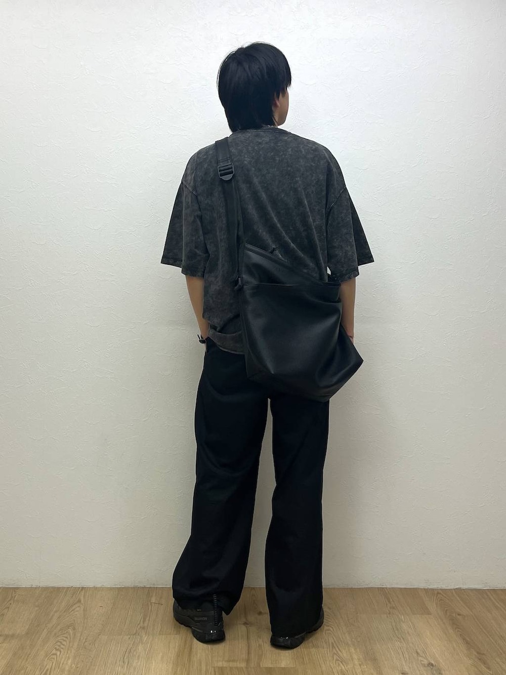 ブラック系のスニーカー、ブラック系のショルダーバッグ、ブラック系のチノパンツを着用したメンズの春コーディネートの3枚目の写真