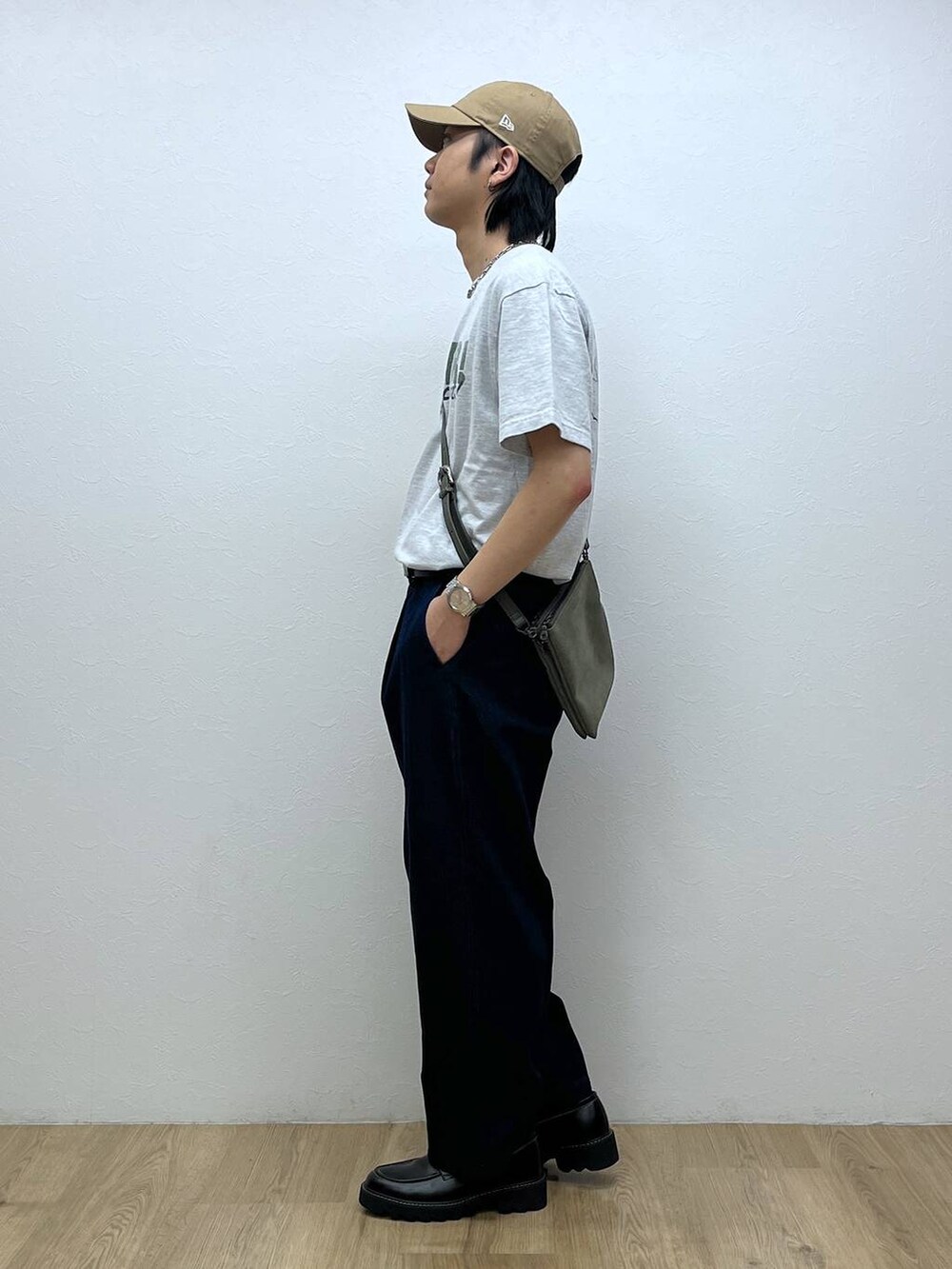 ブラック系のドレスシューズ、ブルー系のデニムパンツ、ベージュ系のショルダーバッグを着用したメンズの春コーディネートの2枚目の写真