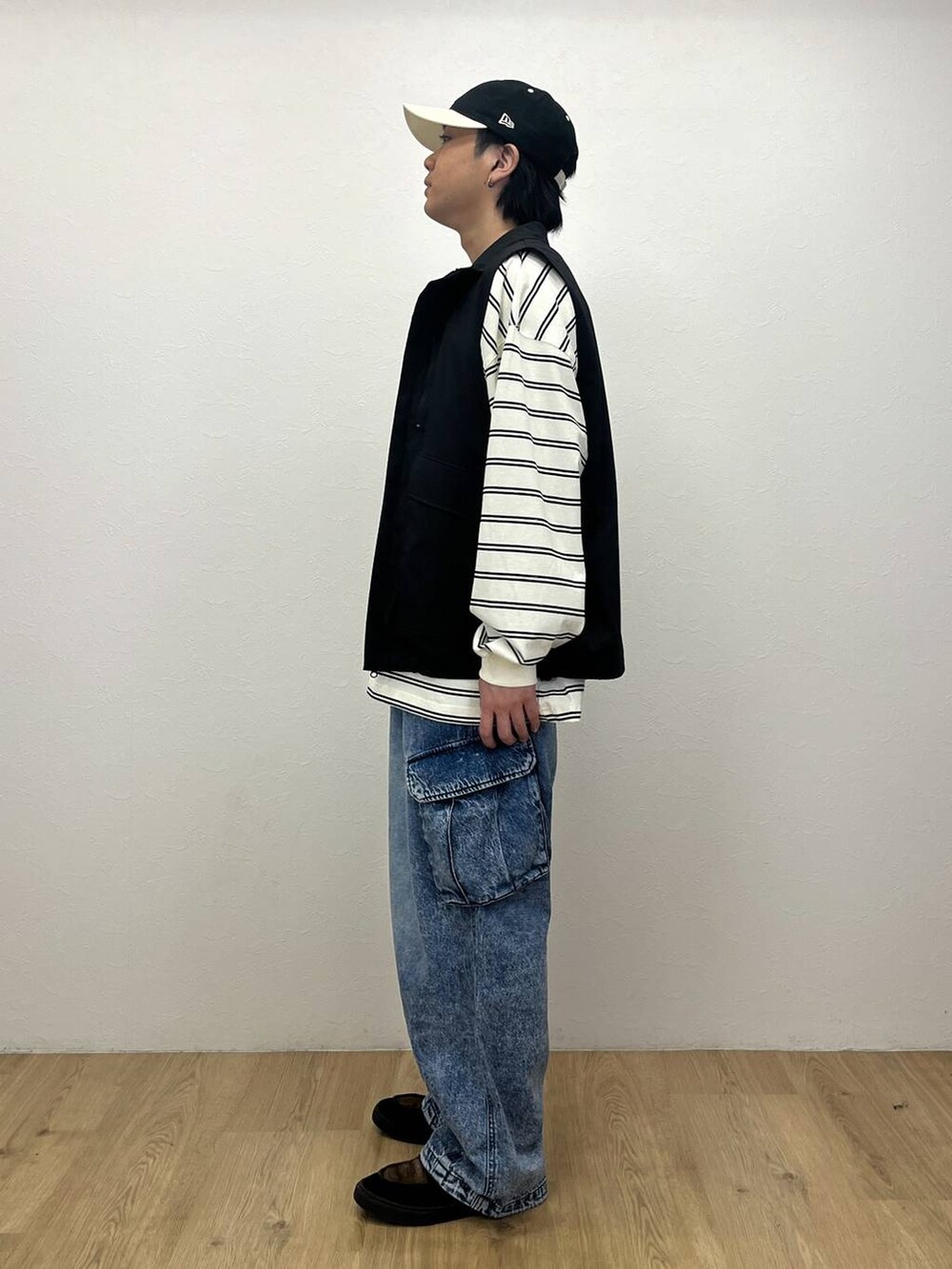 ブラック系のベスト、ホワイト系のTシャツ/カットソー、ブルー系のデニムパンツを着用したメンズの春コーディネートの2枚目の写真