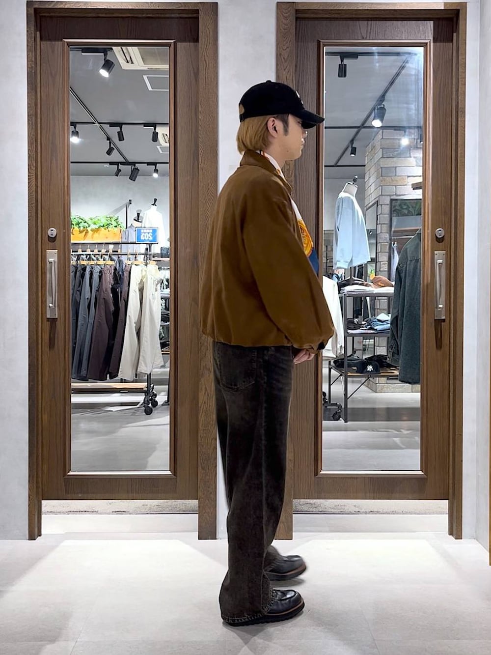 グレー系のデニムパンツ、イエロー系のブルゾン、ブラック系のキャップを着用したメンズの秋コーディネートの2枚目の写真