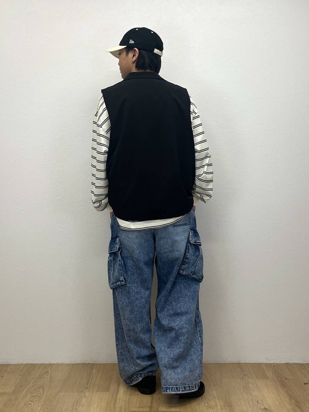 ブラック系のベスト、ホワイト系のTシャツ/カットソー、ブルー系のデニムパンツを着用したメンズの春コーディネートの3枚目の写真