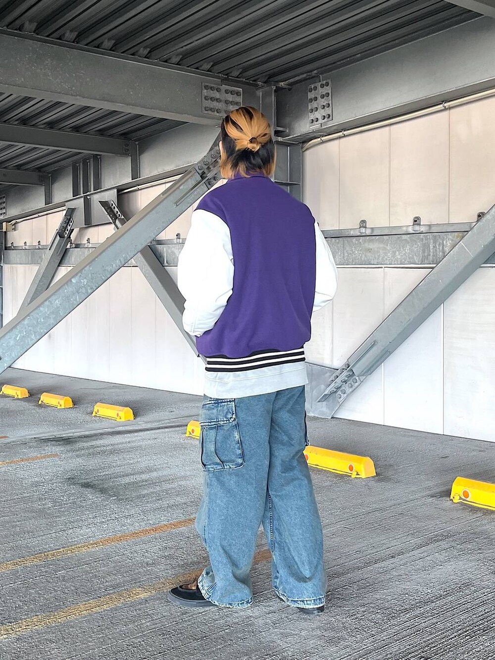 パープル系のスタジャン、ブルー系のデニムパンツ、グレー系のスウェットを着用したメンズの秋コーディネートの3枚目の写真