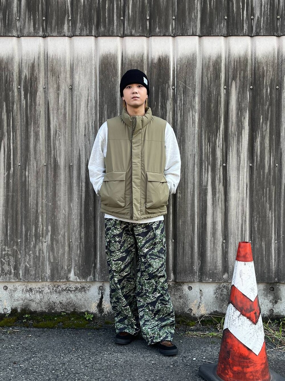 ブラウン系のダウンベスト、グリーン系のカーゴパンツ、ホワイト系のスウェットを着用したメンズの秋コーディネートの4枚目の写真