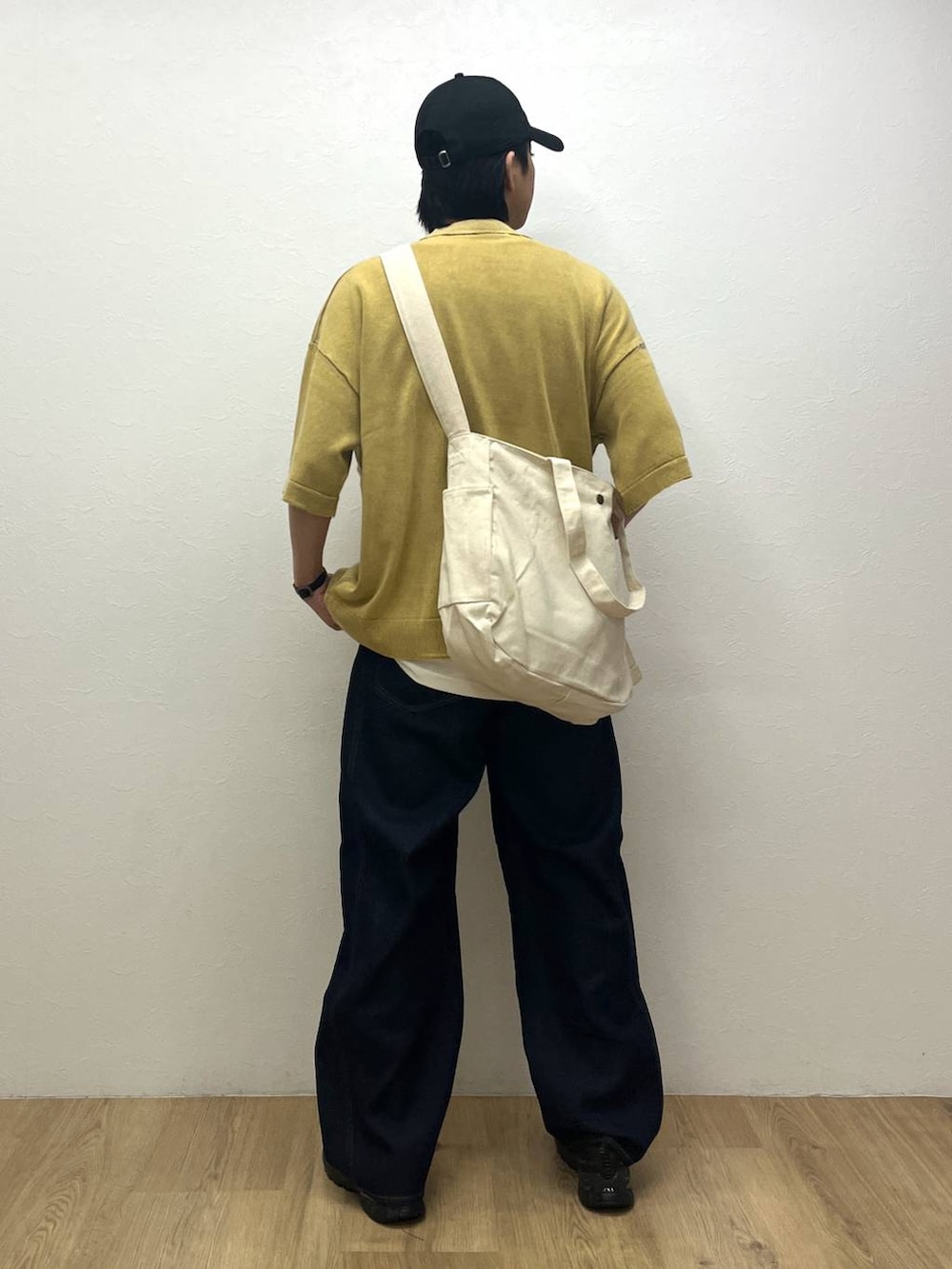 ブラック系のスニーカー、イエロー系のTシャツ/カットソー、ブルー系のデニムパンツを着用したメンズの春コーディネートの3枚目の写真