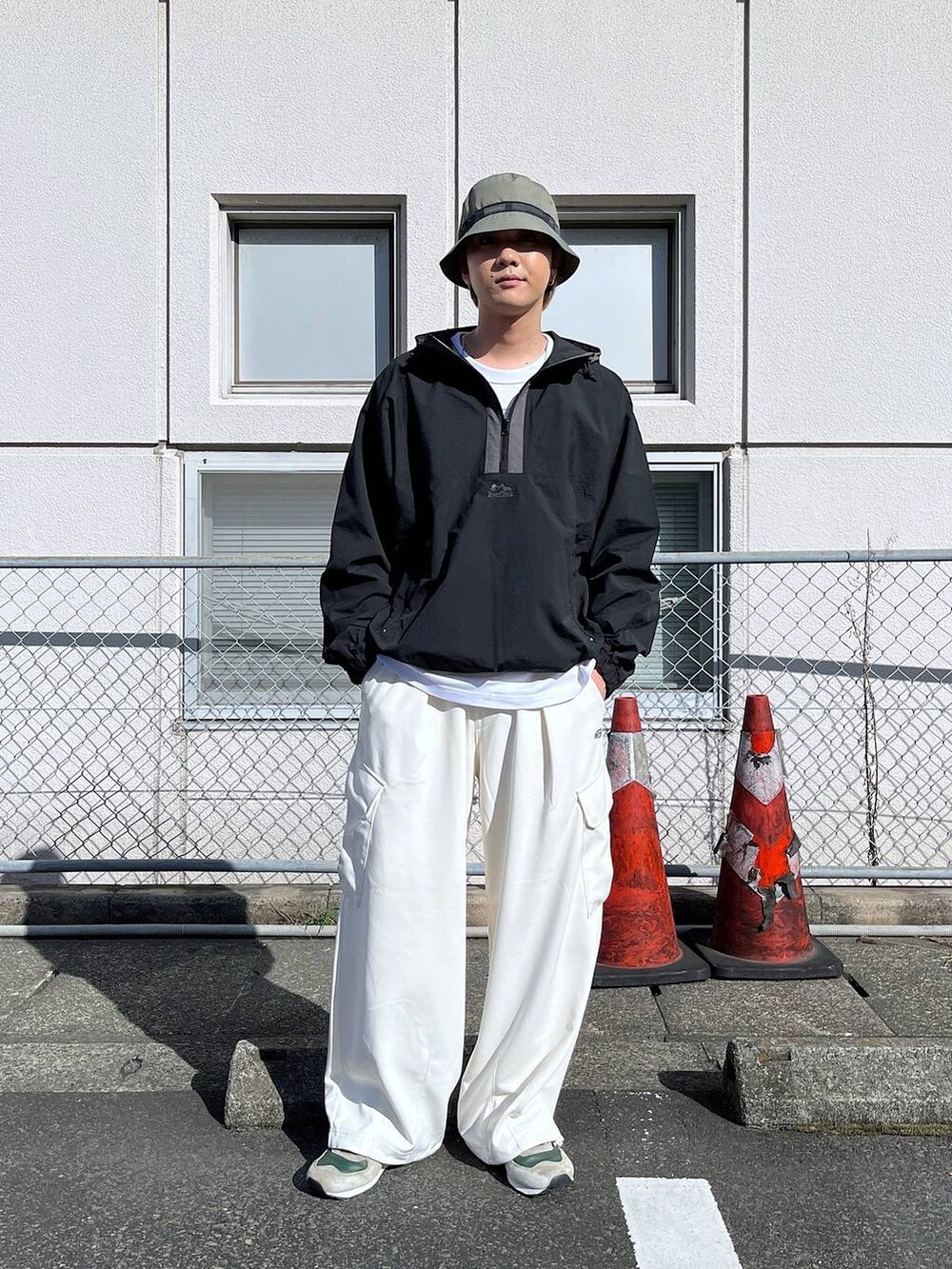 ホワイト系のカーゴパンツ、ブラック系のブルゾン、グリーン系のハットを着用したメンズの秋コーディネートの2枚目の写真