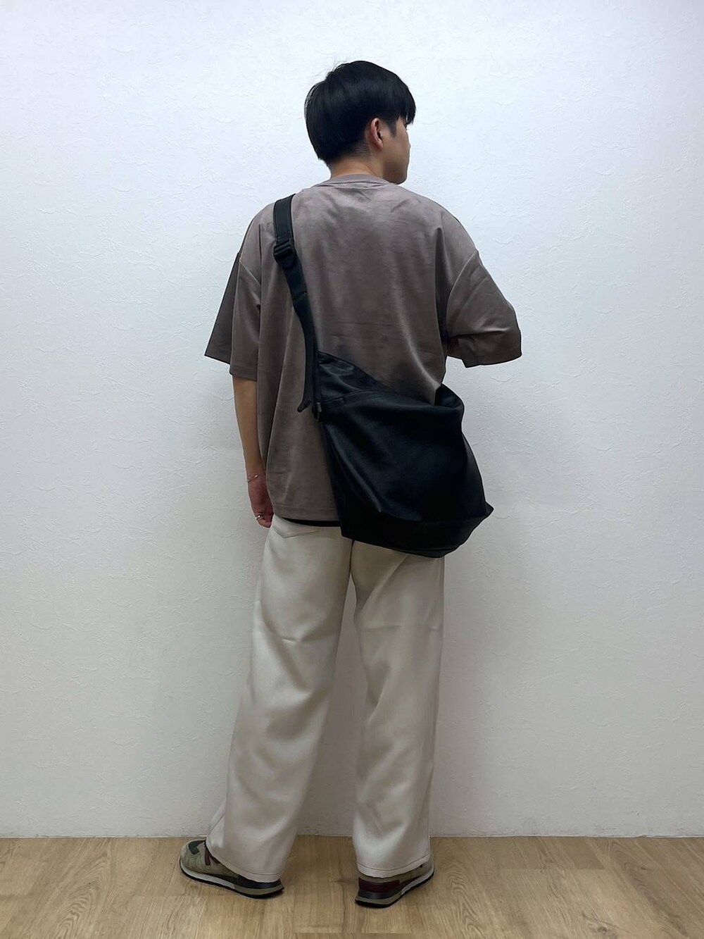 ブラック系のショルダーバッグ、ホワイト系のスラックス、ベージュ系のTシャツ/カットソーを着用したメンズの夏コーディネートの3枚目の写真