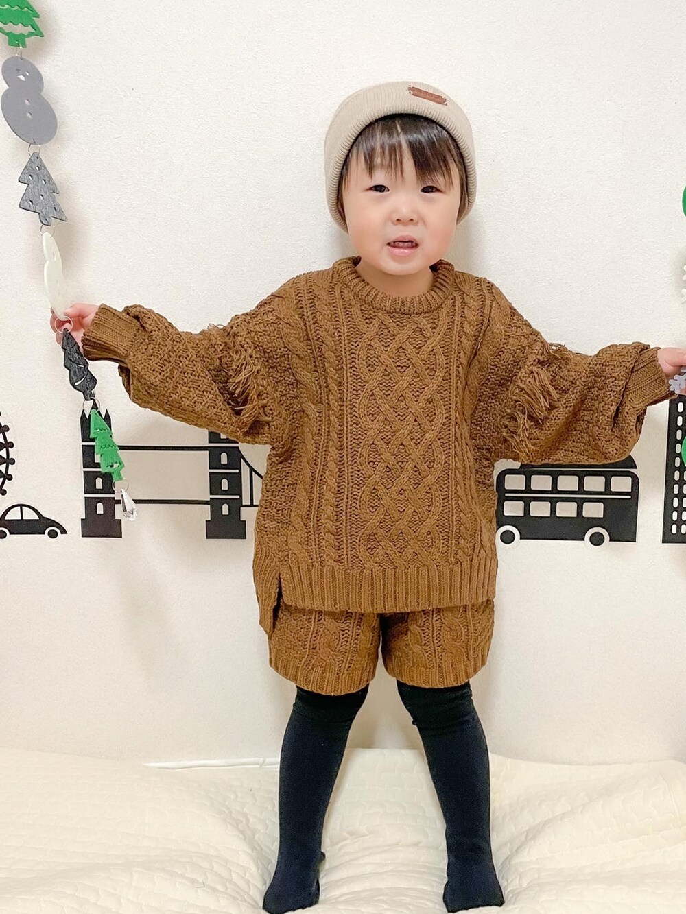 ブラウン系のニット/セーター、ブラウン系のその他パンツ、ベージュ系のニットキャップ/ビーニーを着用したキッズの冬コーディネートの2枚目の写真