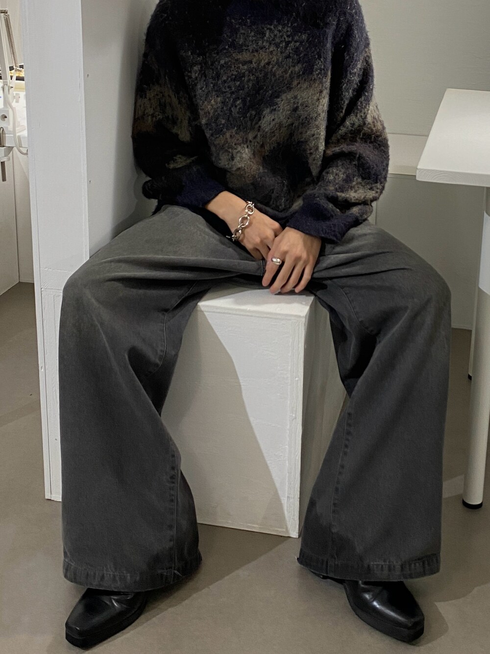 ブラウン系のニット/セーター、グレー系のスラックス、ブラック系のブーツを着用したメンズの秋コーディネートの2枚目の写真