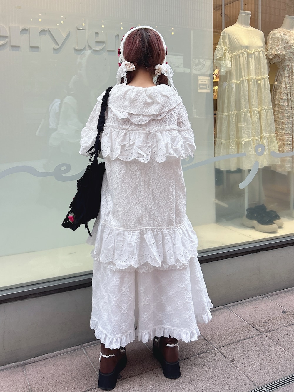 ホワイト系のテーラードジャケット、ホワイト系のスカート、ブラック系のショルダーバッグを着用したレディースの夏コーディネートの2枚目の写真