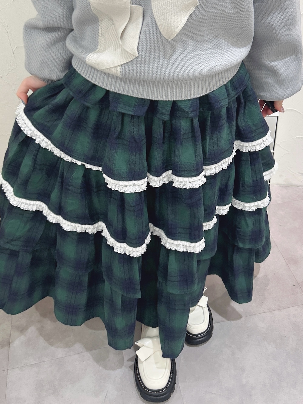 ブルー系のニット/セーター、ホワイト系のシャツ/ブラウス、グリーン系のスカートを着用したレディースの秋コーディネートの9枚目の写真