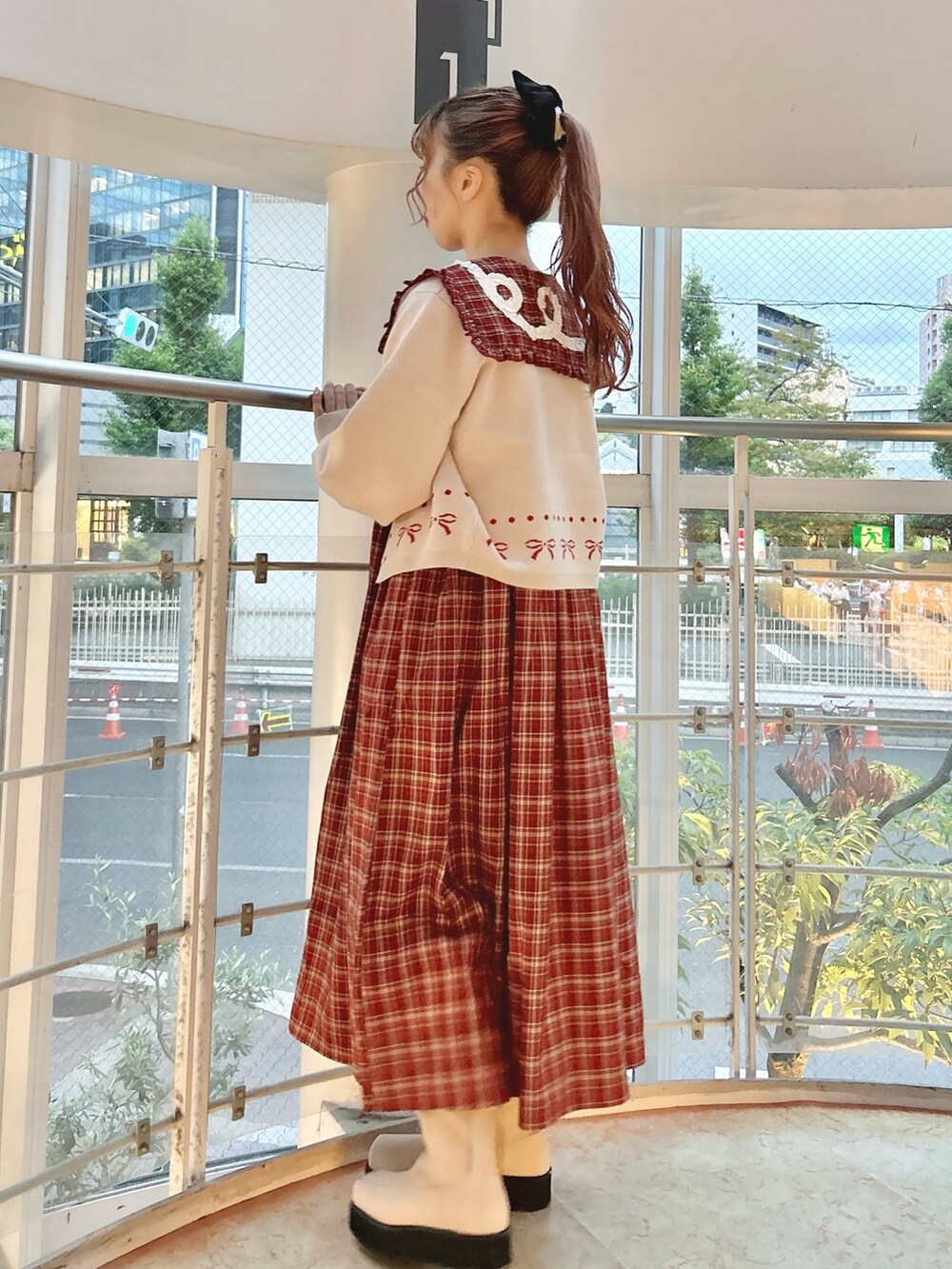 レッド系のワンピース、ホワイト系のカーディガン/ボレロ、ピンク系のブーツを着用したレディースの秋コーディネートの4枚目の写真