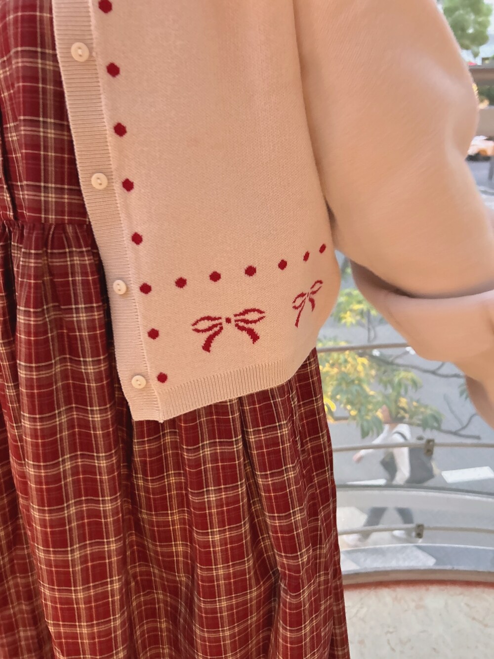 レッド系のワンピース、ホワイト系のカーディガン/ボレロ、ピンク系のブーツを着用したレディースの秋コーディネートの9枚目の写真