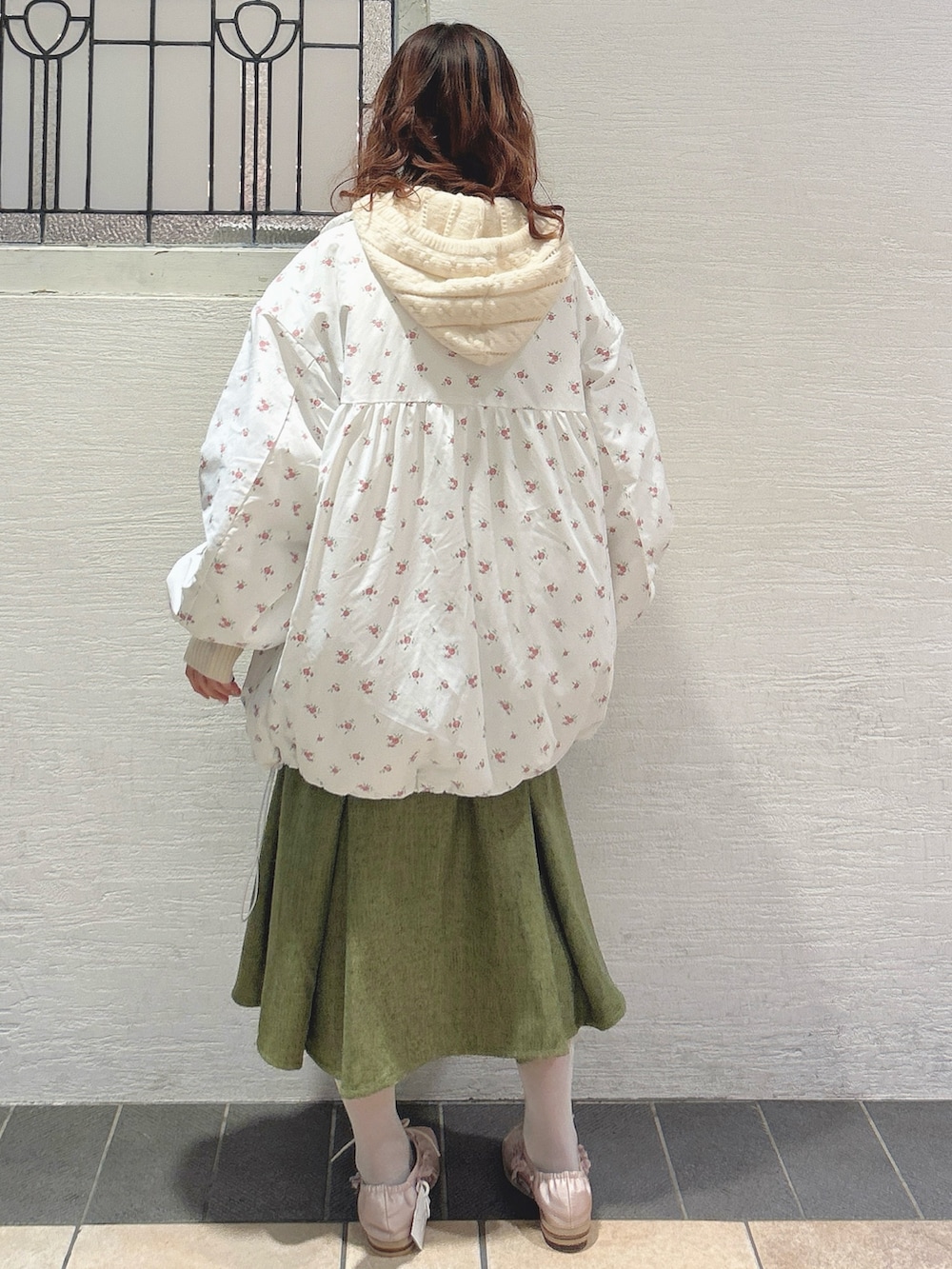 ピンク系のブルゾン、ホワイト系のニット/セーター、グリーン系のスカートを着用したレディースの秋コーディネートの3枚目の写真