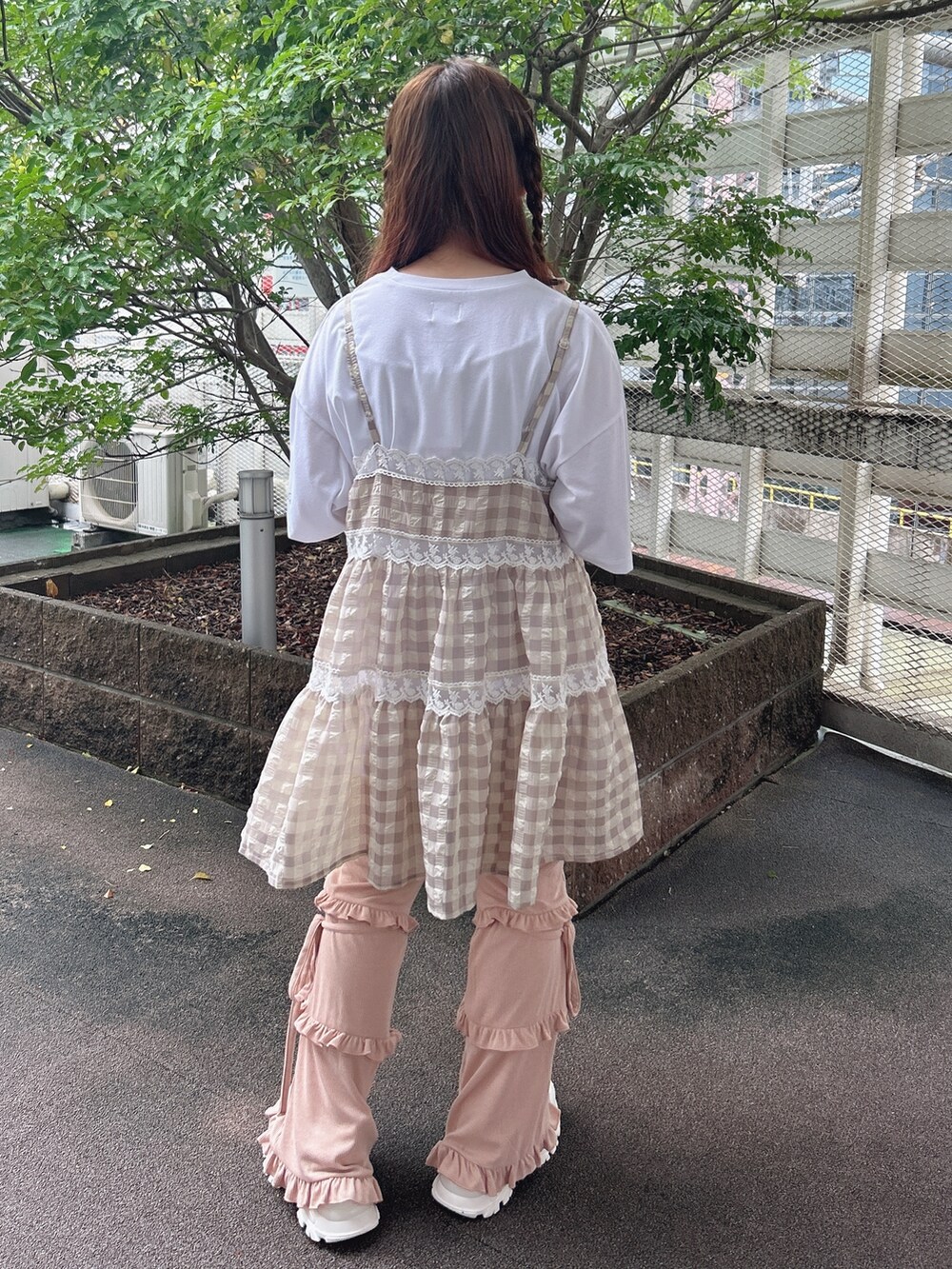 ピンク系のスウェットパンツ、ホワイト系のスニーカー、ベージュ系のキャミソールを着用したレディースの夏コーディネートの3枚目の写真