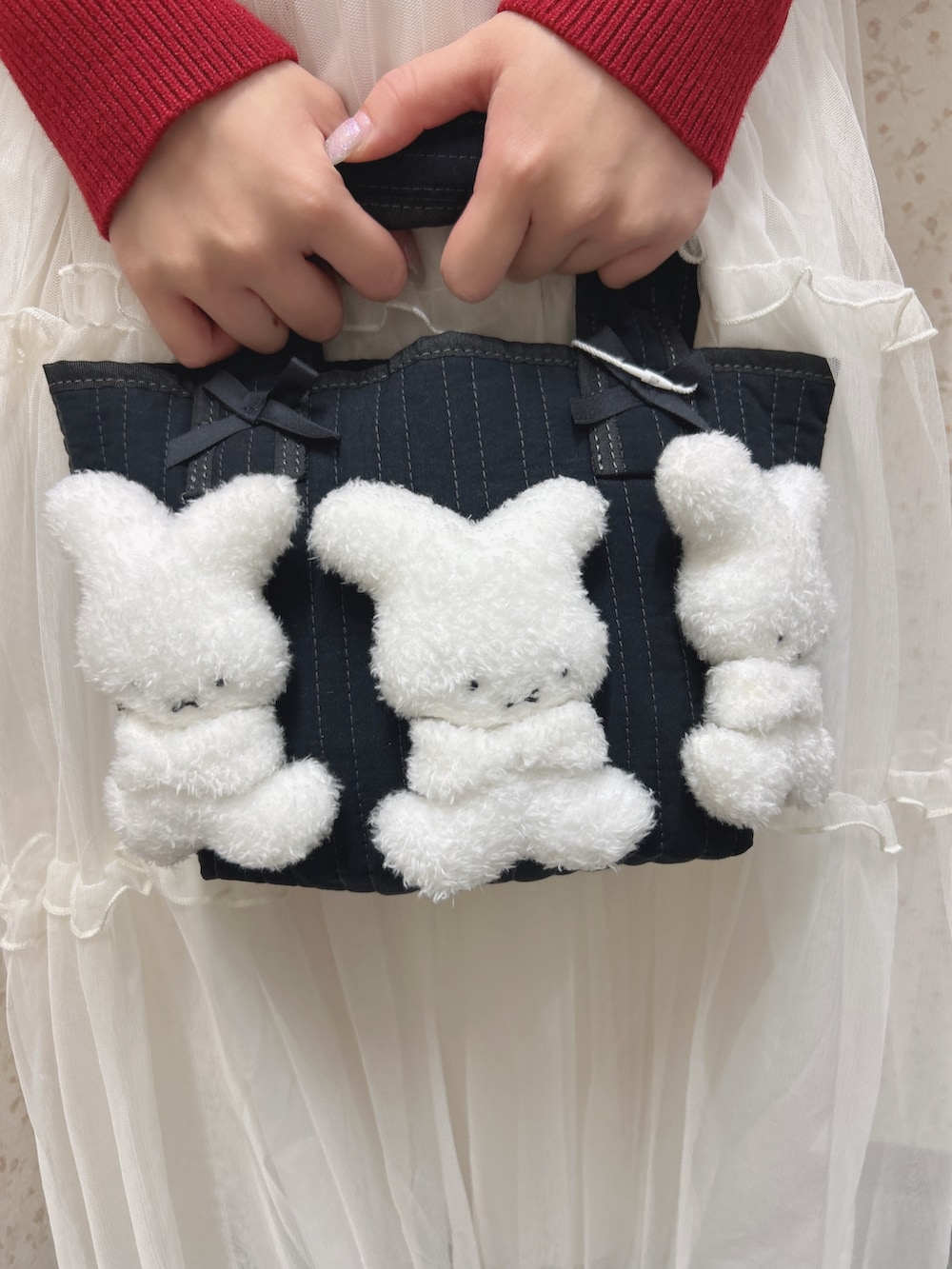 レッド系のニット/セーター、ホワイト系のワンピース、ブラック系のトートバッグを着用したレディースの秋コーディネートの9枚目の写真