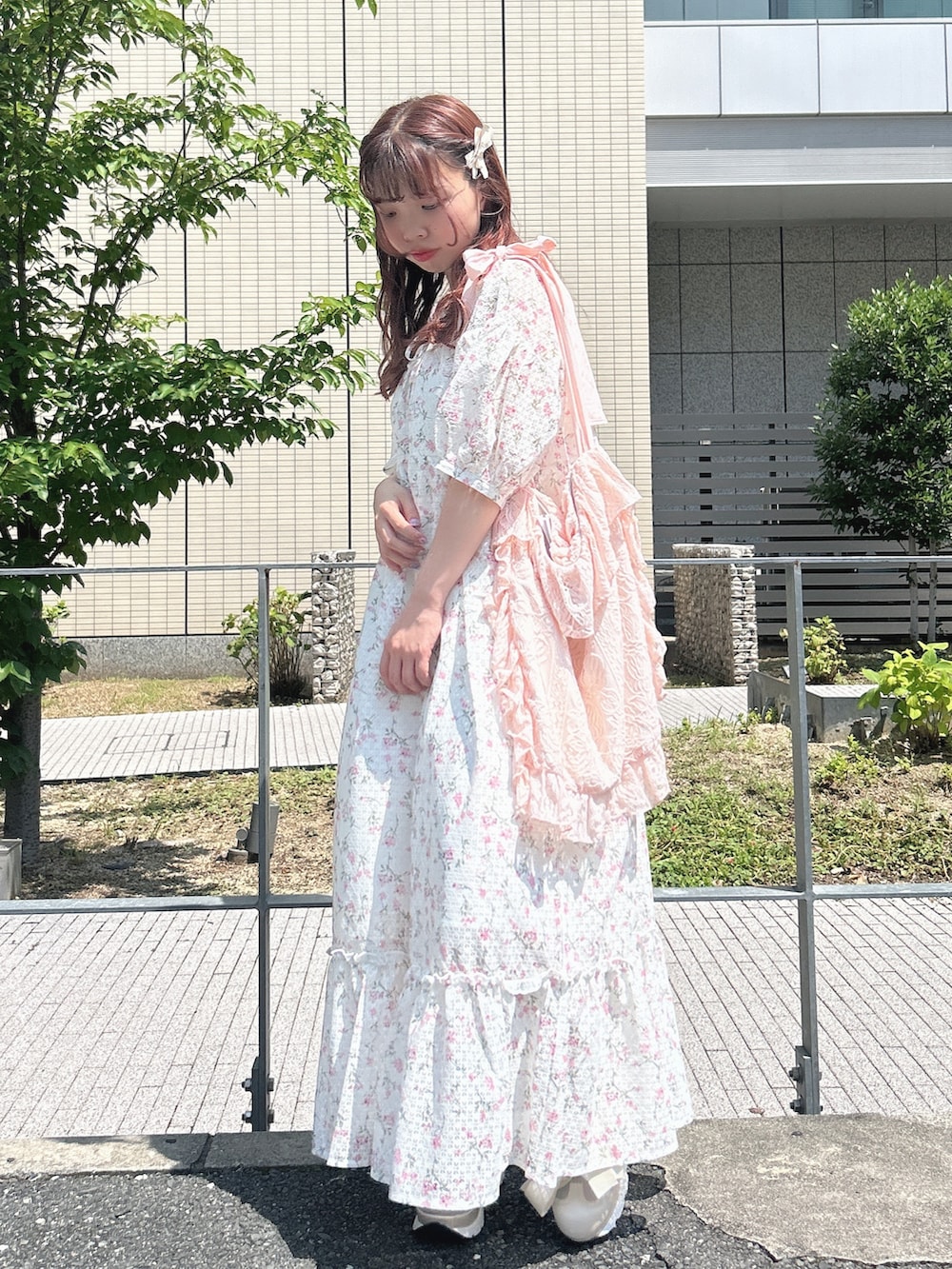 ピンク系のワンピース、ピンク系のトートバッグ、ホワイト系のスニーカーを着用したレディースの夏コーディネートの2枚目の写真