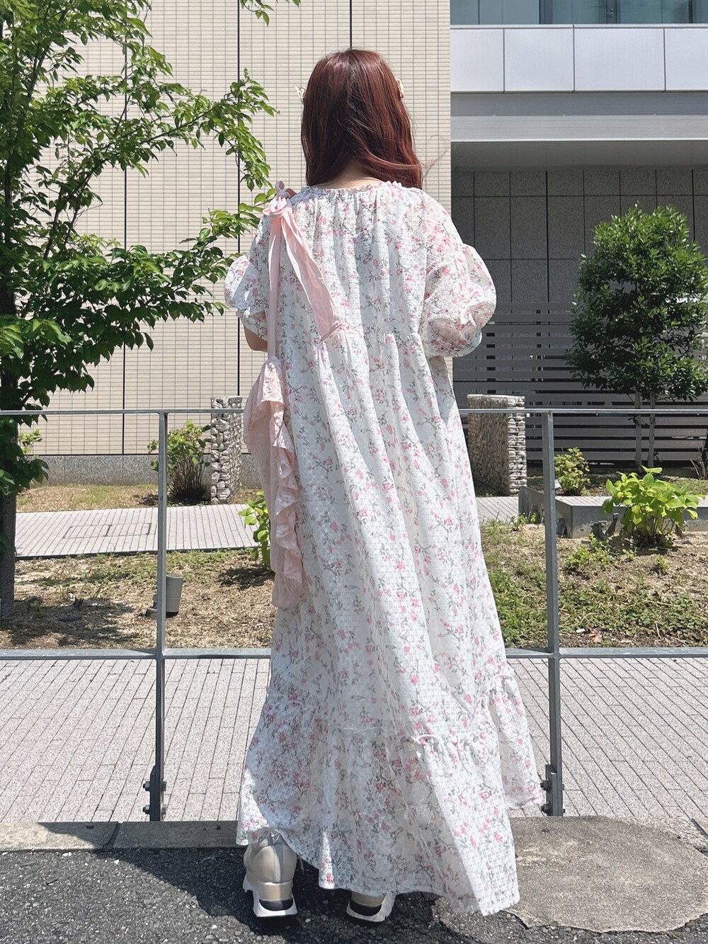 ピンク系のワンピース、ピンク系のトートバッグ、ホワイト系のスニーカーを着用したレディースの夏コーディネートの3枚目の写真