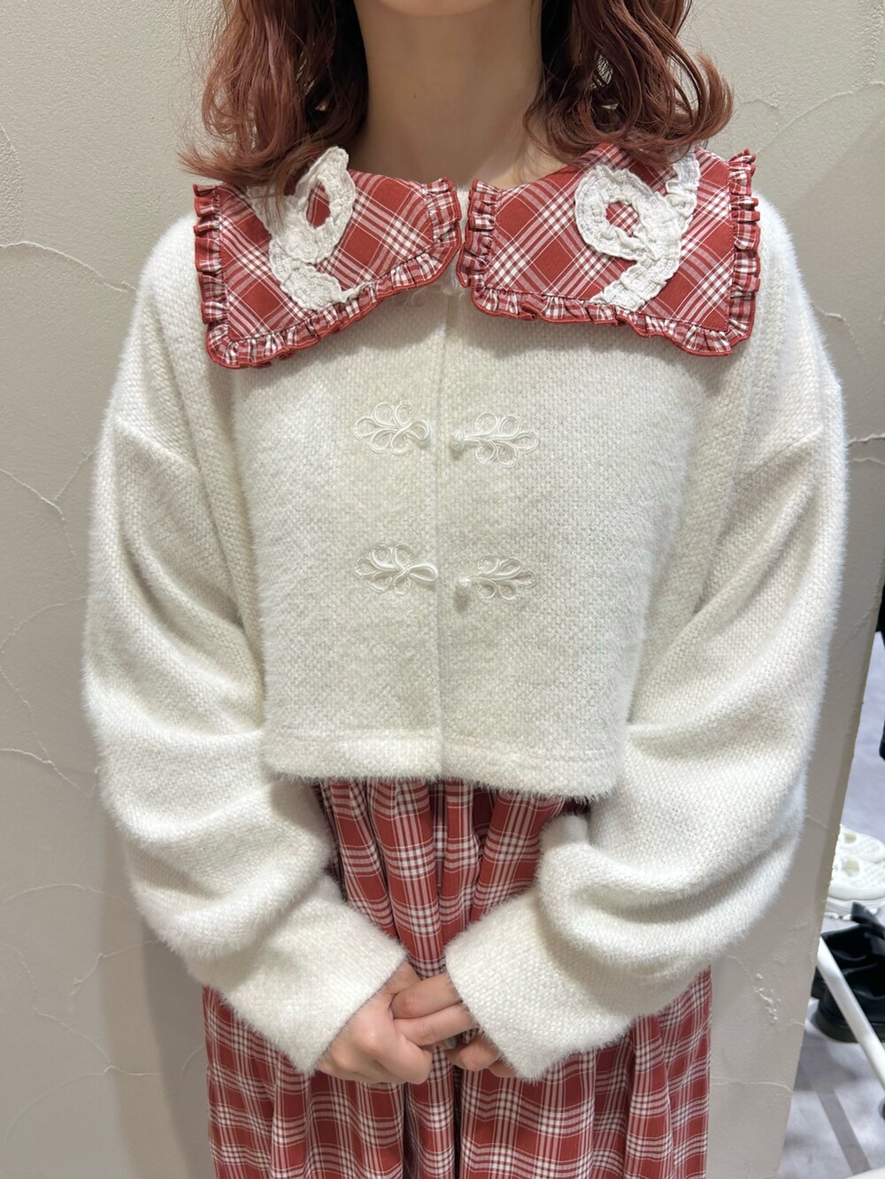 レッド系のワンピース、ホワイト系のカーディガン/ボレロ、ホワイト系のスニーカーを着用したレディースの秋コーディネートの6枚目の写真