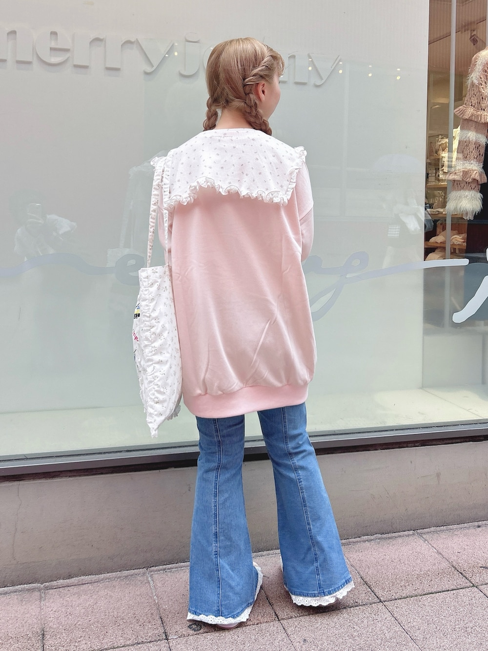 ピンク系のスウェット、ブルー系のデニムパンツ、ホワイト系のトートバッグを着用したレディースの秋コーディネートの2枚目の写真