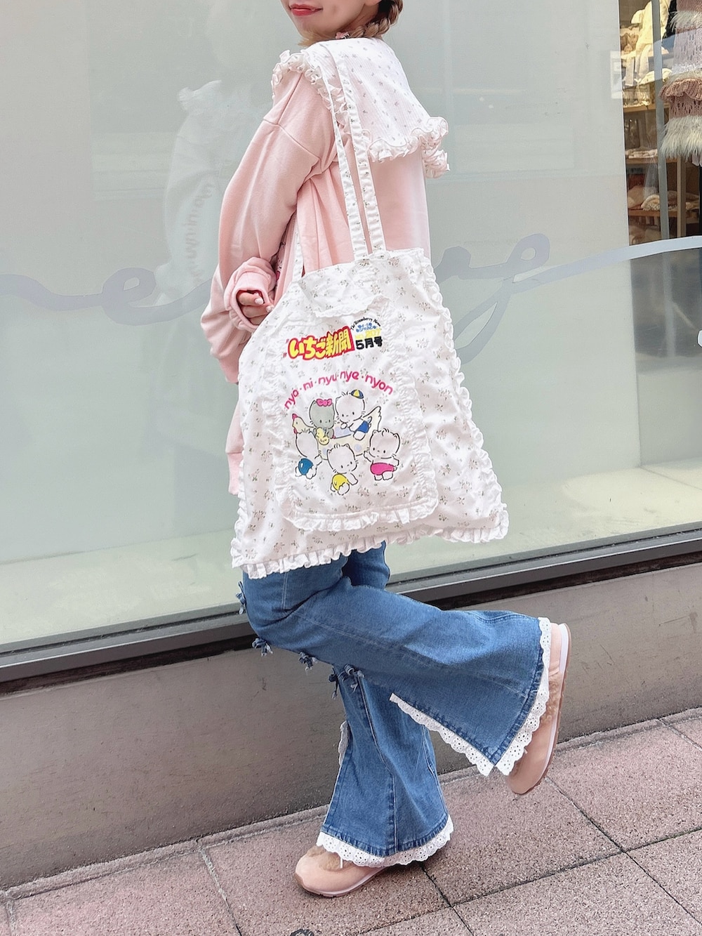 ピンク系のスウェット、ブルー系のデニムパンツ、ホワイト系のトートバッグを着用したレディースの秋コーディネートの3枚目の写真