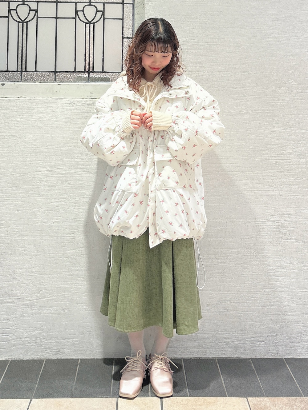 ピンク系のブルゾン、ホワイト系のニット/セーター、グリーン系のスカートを着用したレディースの秋コーディネートの2枚目の写真