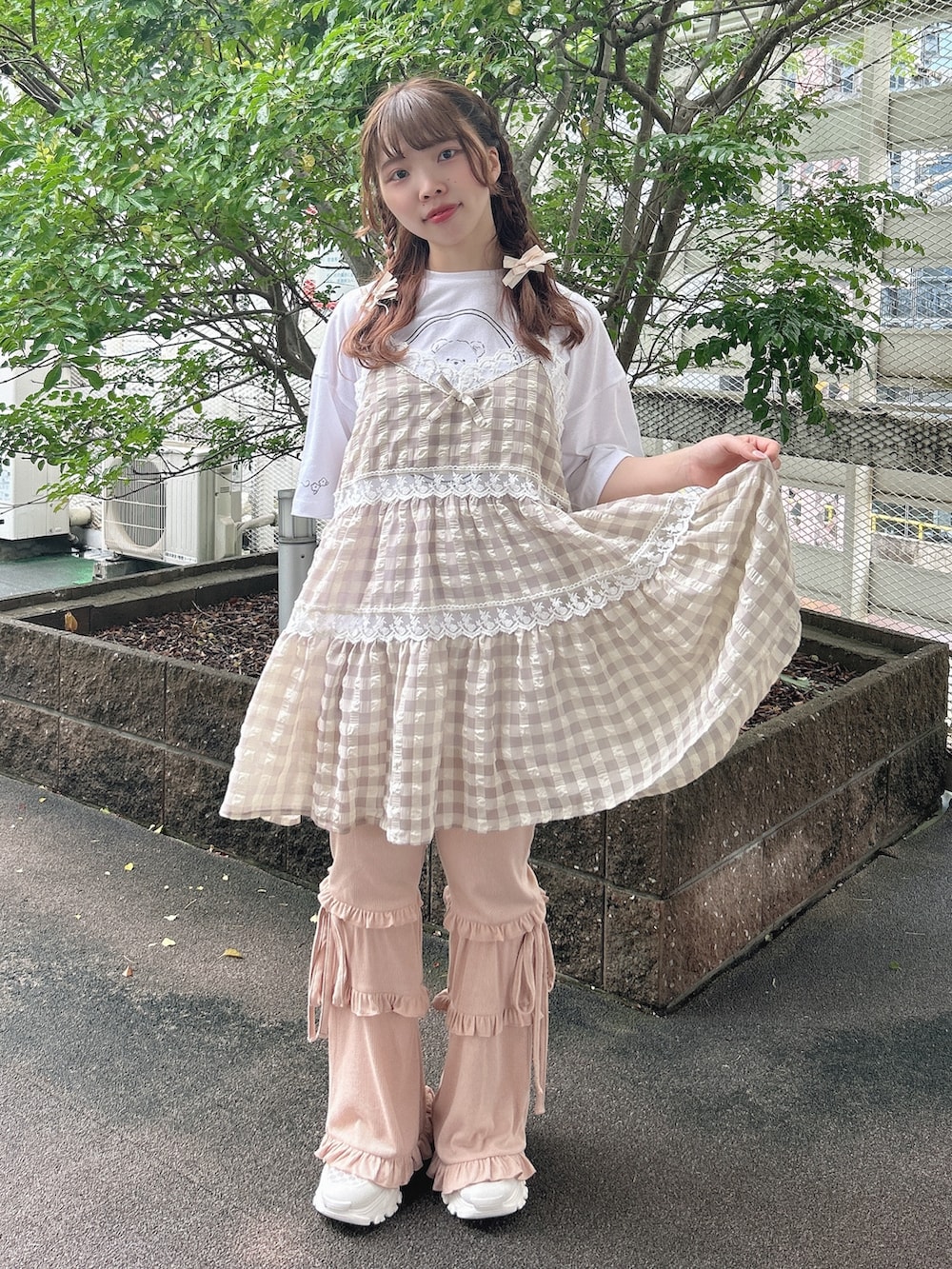 ピンク系のスウェットパンツ、ホワイト系のスニーカー、ベージュ系のキャミソールを着用したレディースの夏コーディネートの2枚目の写真