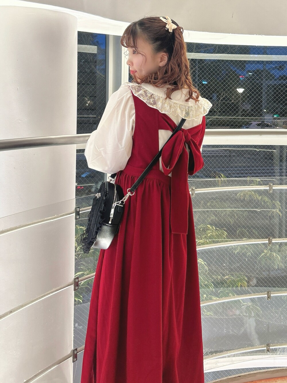 レッド系のワンピース、ゴールド系のシャツ/ブラウス、ブラック系のショルダーバッグを着用したレディースの秋コーディネートの5枚目の写真