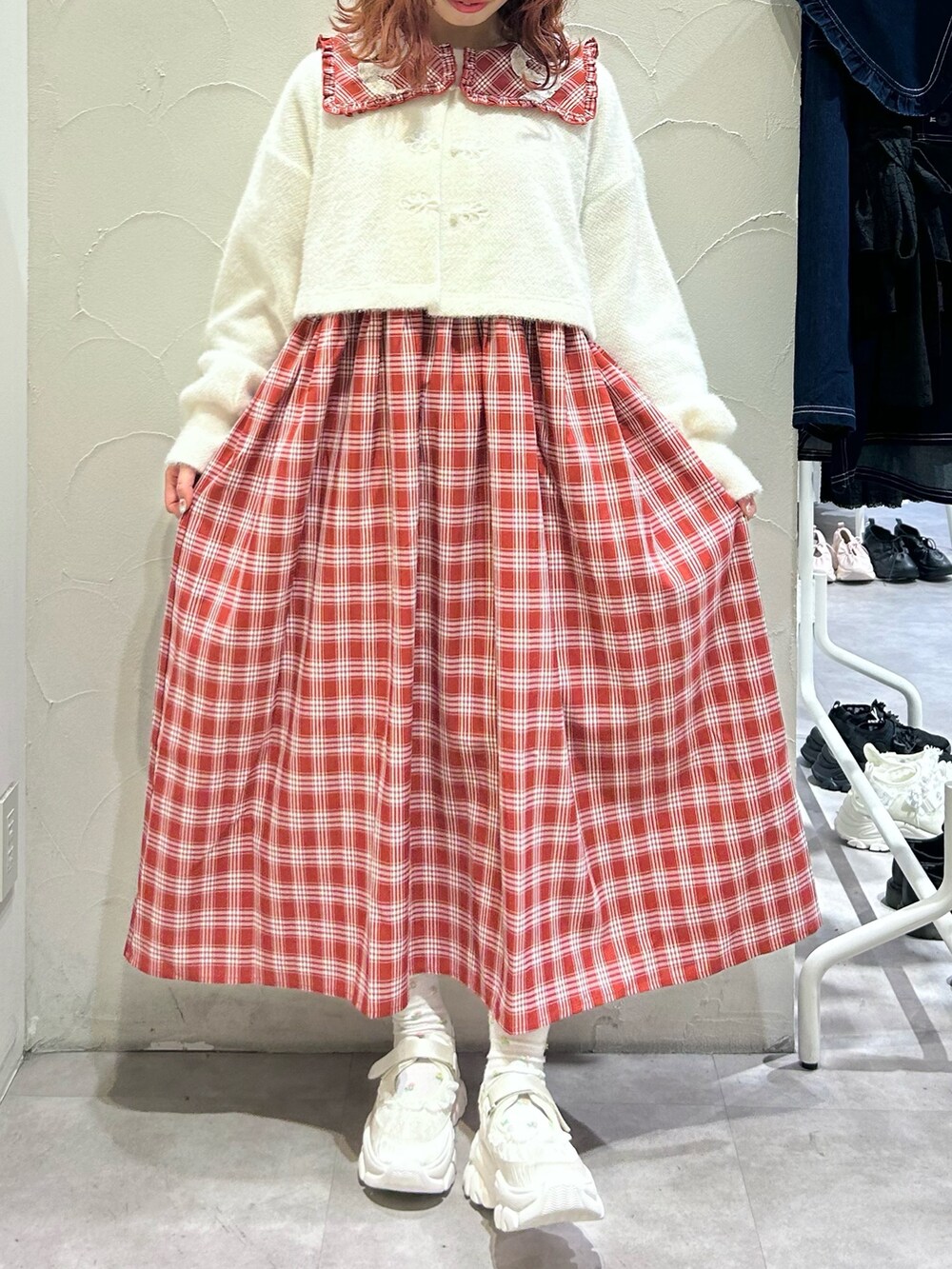 レッド系のワンピース、ホワイト系のカーディガン/ボレロ、ホワイト系のスニーカーを着用したレディースの秋コーディネートの3枚目の写真