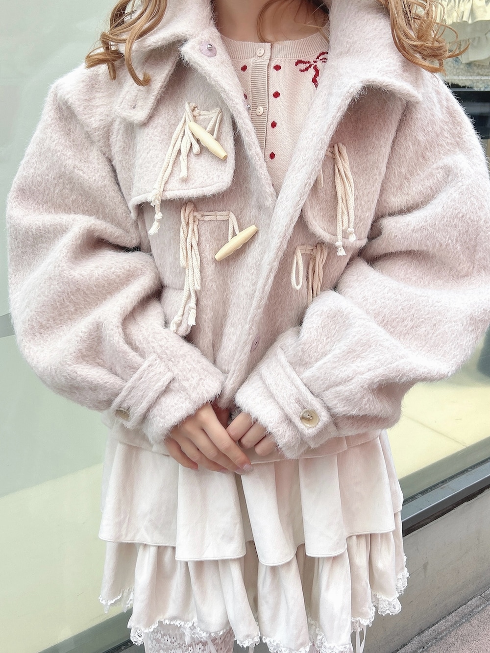 ホワイト系のスカート、ピンク系のダッフルコート、ホワイト系のカーディガン/ボレロを着用したレディースの秋コーディネートの8枚目の写真