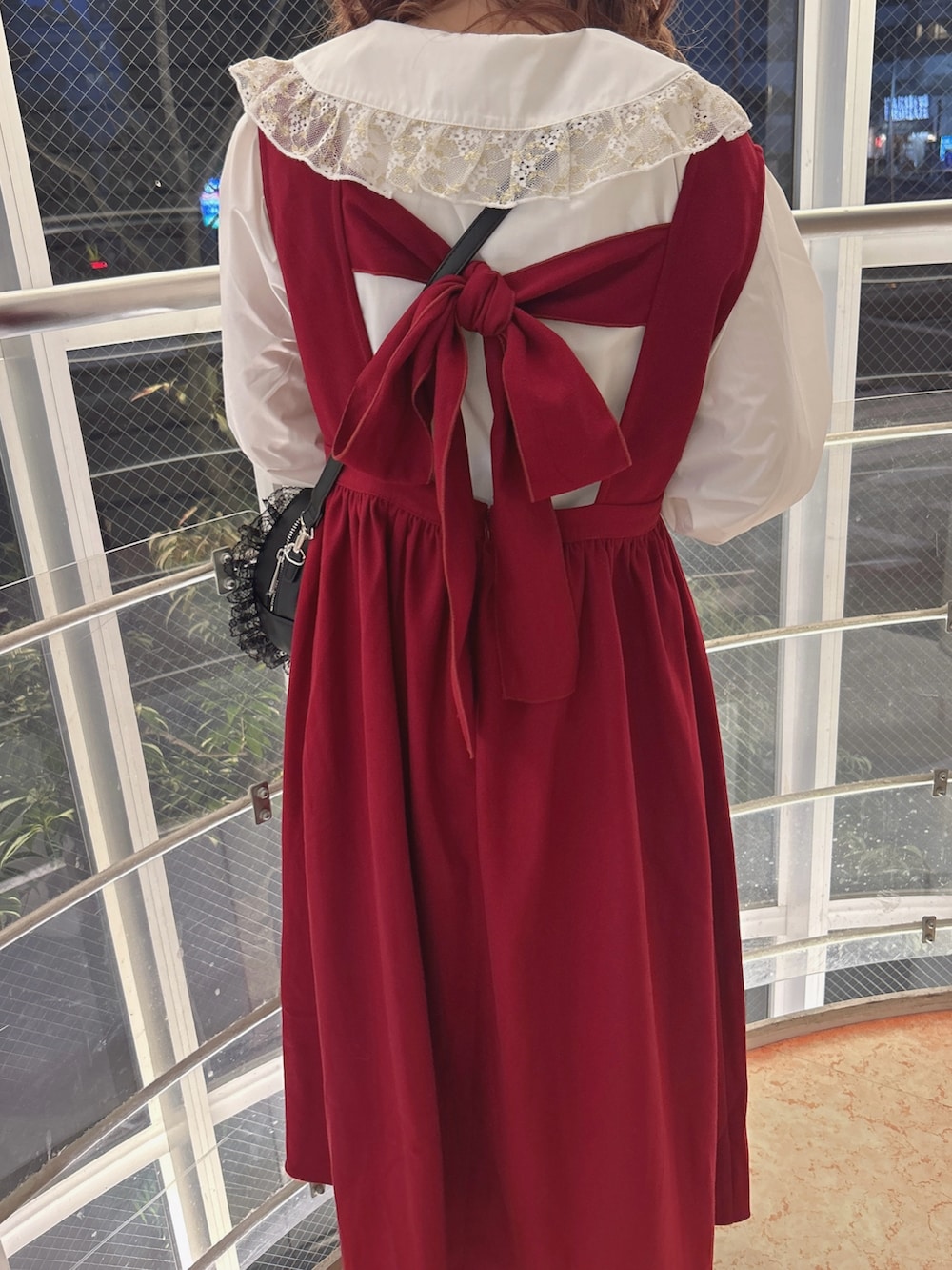 レッド系のワンピース、ゴールド系のシャツ/ブラウス、ブラック系のショルダーバッグを着用したレディースの秋コーディネートの9枚目の写真