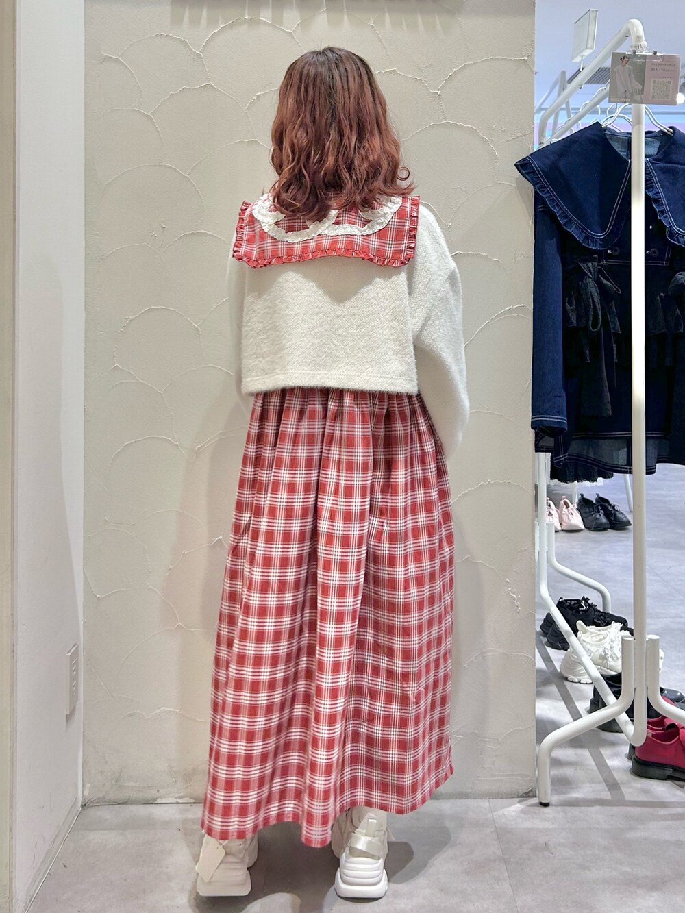 レッド系のワンピース、ホワイト系のカーディガン/ボレロ、ホワイト系のスニーカーを着用したレディースの秋コーディネートの2枚目の写真