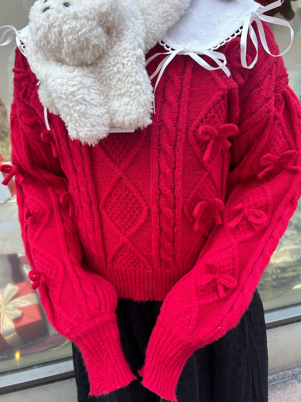 ホワイト系のブルゾン、レッド系のニット/セーター、ブラック系のワンピースを着用したレディースの冬コーディネートの9枚目の写真